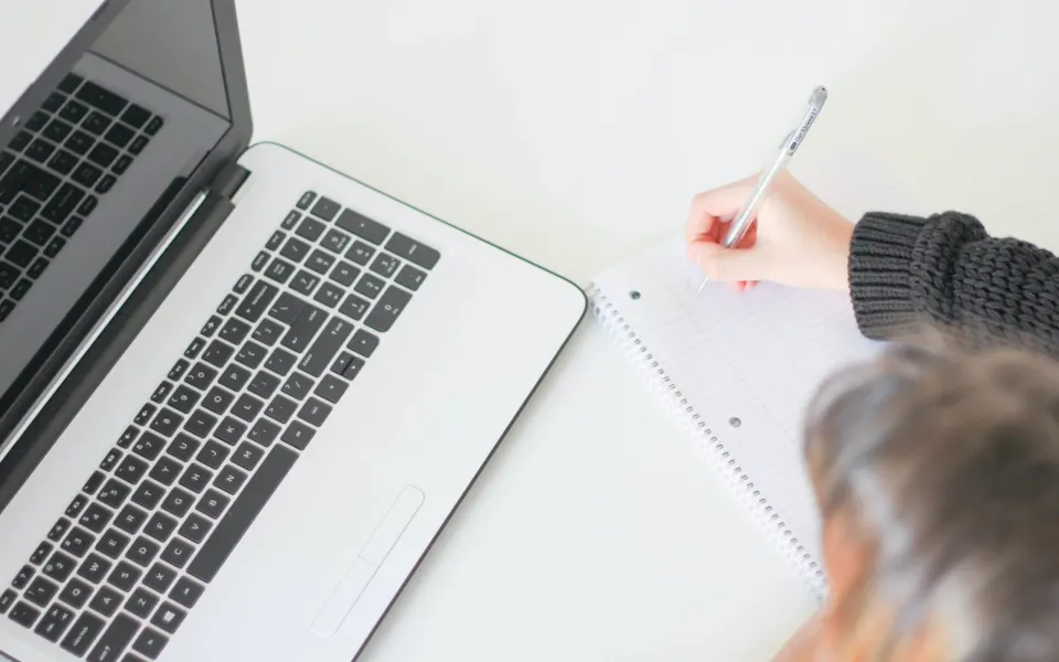 Personne prenant des notes à côté d’un ordinateur portable : bien écrire pour le web et le SEO