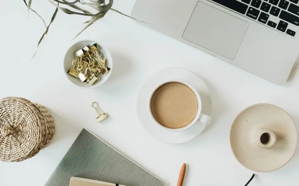Bureau vu de dessus avec ordinateur portable, café et carnet : préparer sa stratégie de content marketing